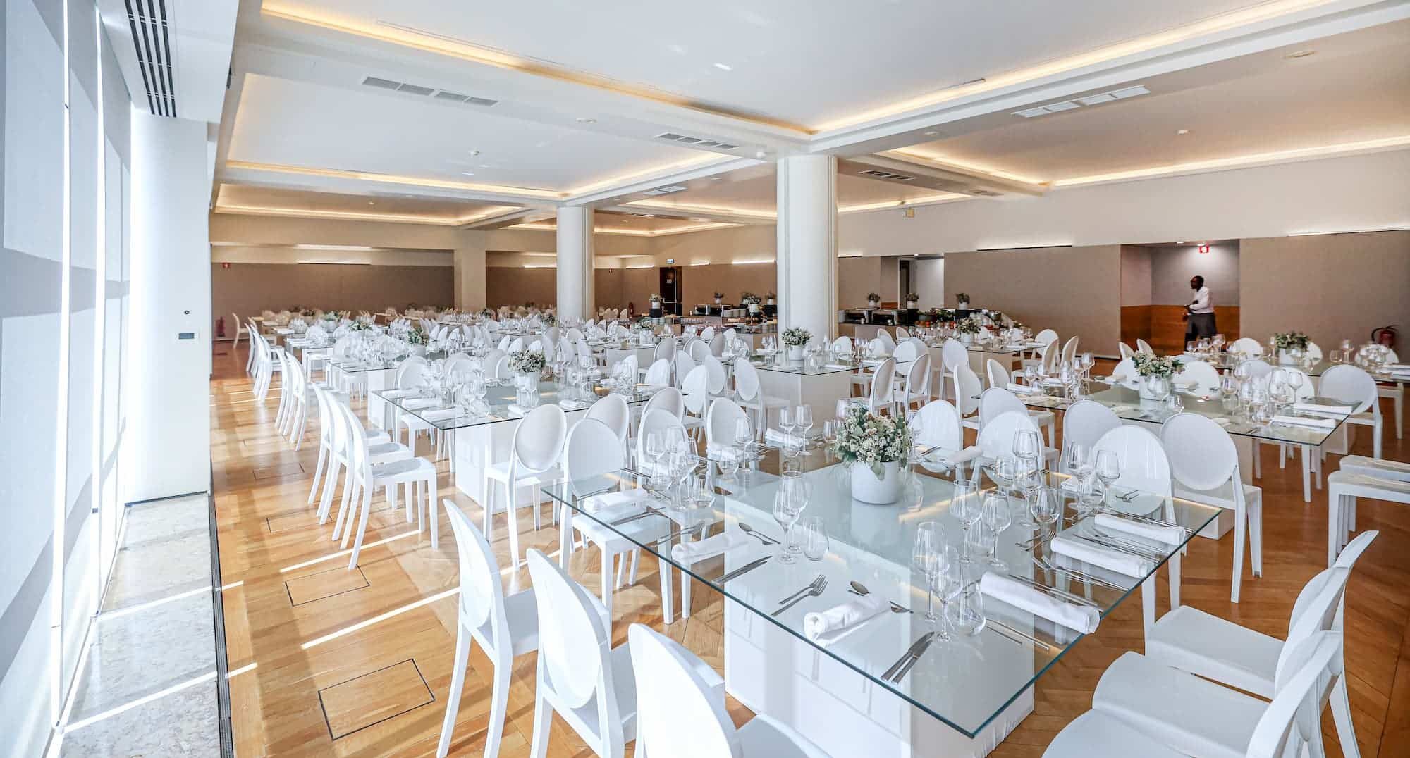 http://Sala%20Vitorino%20Nemésio%20preparada%20com%20mesas%20e%20cadeiras%20brancas%20para%20evento,%20decorado%20com%20flores%20e%20utensílios%20de%20jantar%20elegantes,%20ideal%20para%20casamento%20ou%20comemoração.