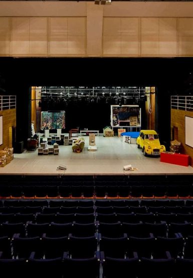 vista de toda a plateia do pequeno auditório com alguns objetos em cima do palco que vão servir para uma peça de teatro