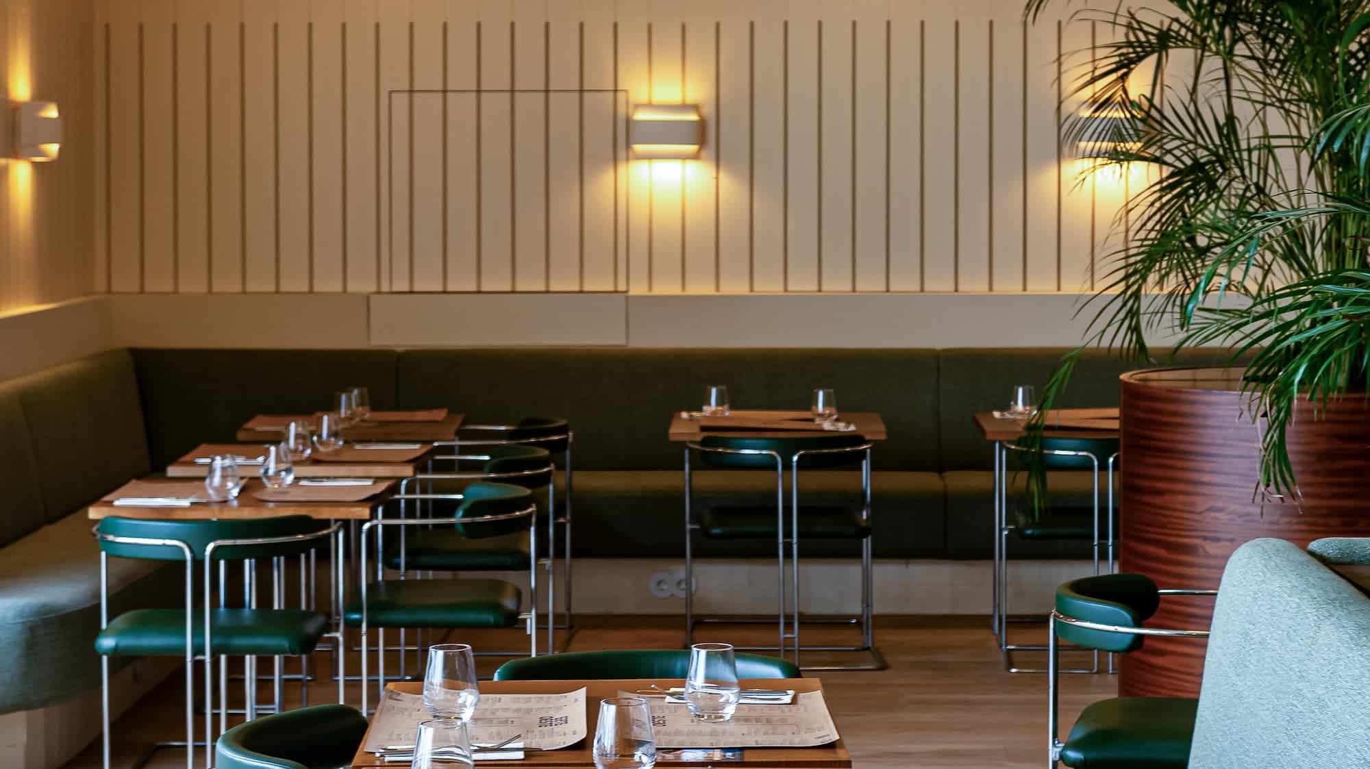 http://Interior%20do%20restaurante%20EsteOeste%20moderno%20com%20decoração%20aconchegante,%20mesas%20bem%20arrumadas%20com%20copos%20e%20talheres,%20iluminação%20suave%20e%20plantas%20decorativas.