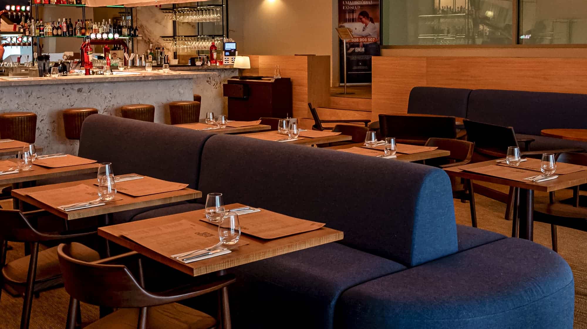 http://Interior%20de%20restaurante%20EsteOeste%20sofisticado%20com%20mesas%20bem%20decoradas,%20cadeiras%20confortáveis%20e%20ambiente%20acolhedor,%20ideal%20para%20jantar%20romântico%20ou%20encontros%20sociais.